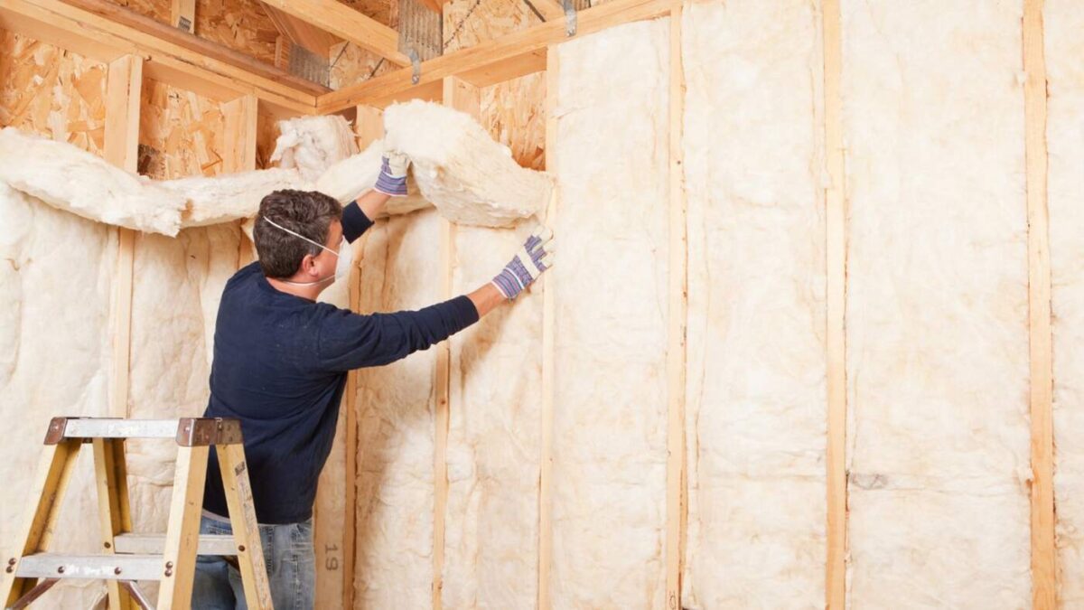 A technician installing insulation in an existing wall