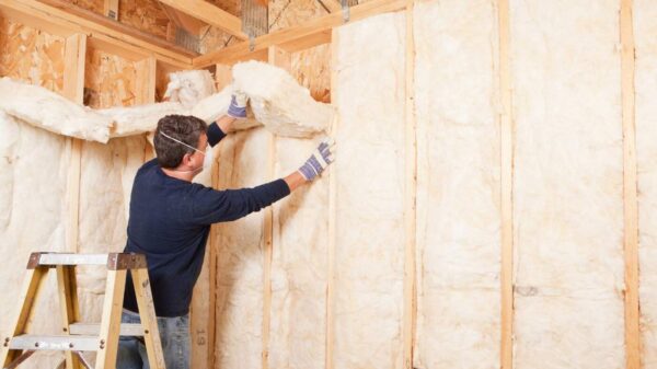 A technician installing insulation in an existing wall